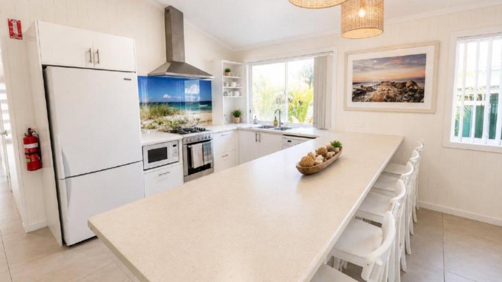 a kitchen with a white refrigerator and a table at Sandy Feet in Wooli