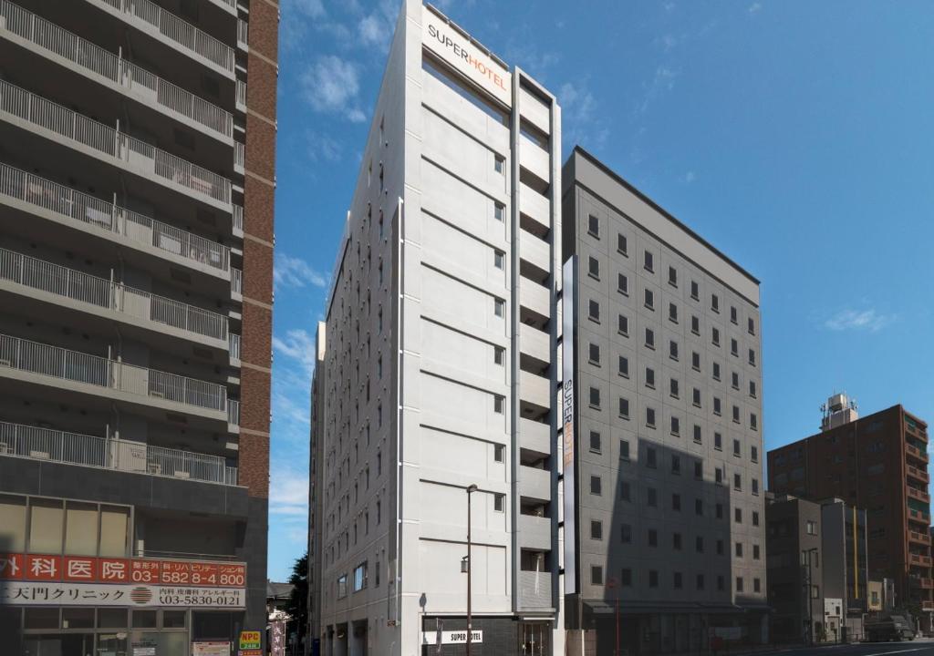 a tall white building next to two tall buildings at Super Hotel Asakusa in Tokyo