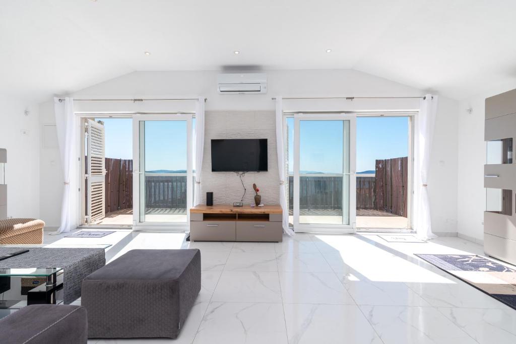 a living room with a tv and large windows at Monte Mare in Donji Seget