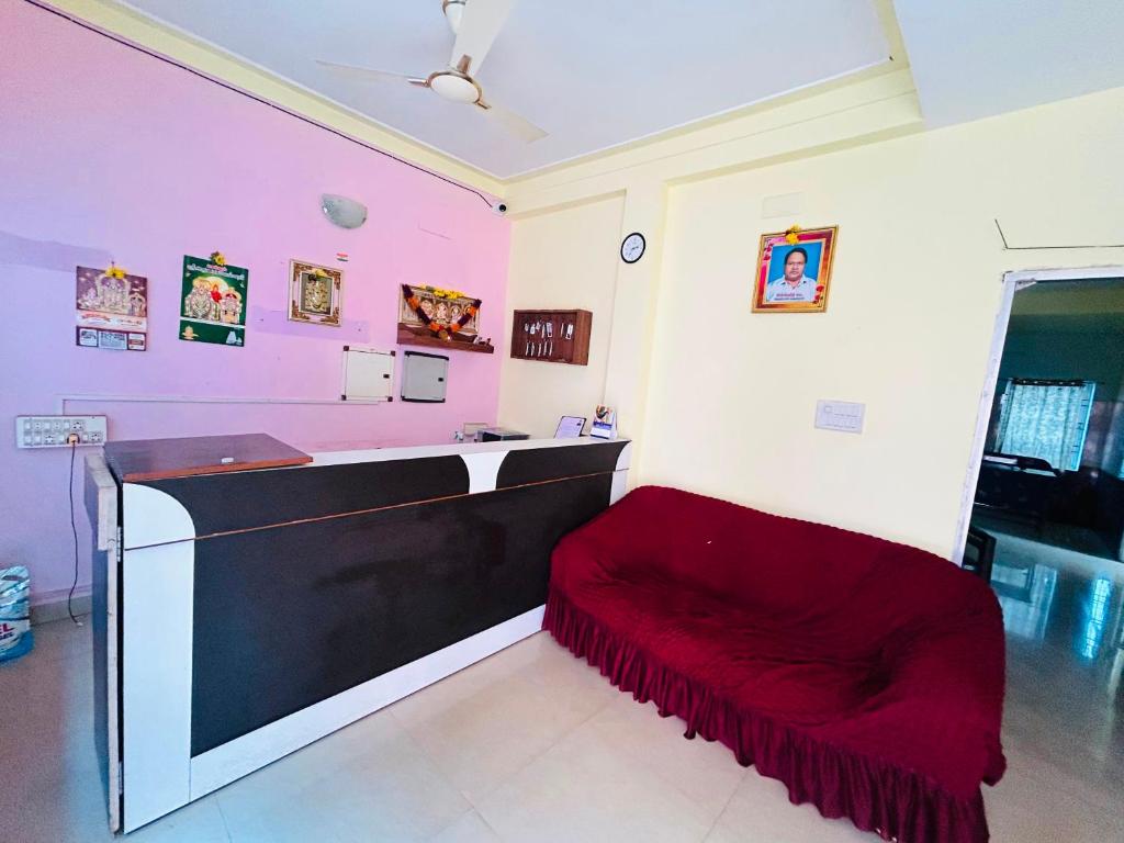 a kitchen with pink walls and a red couch at Breezevalley Residency in Yelagiri