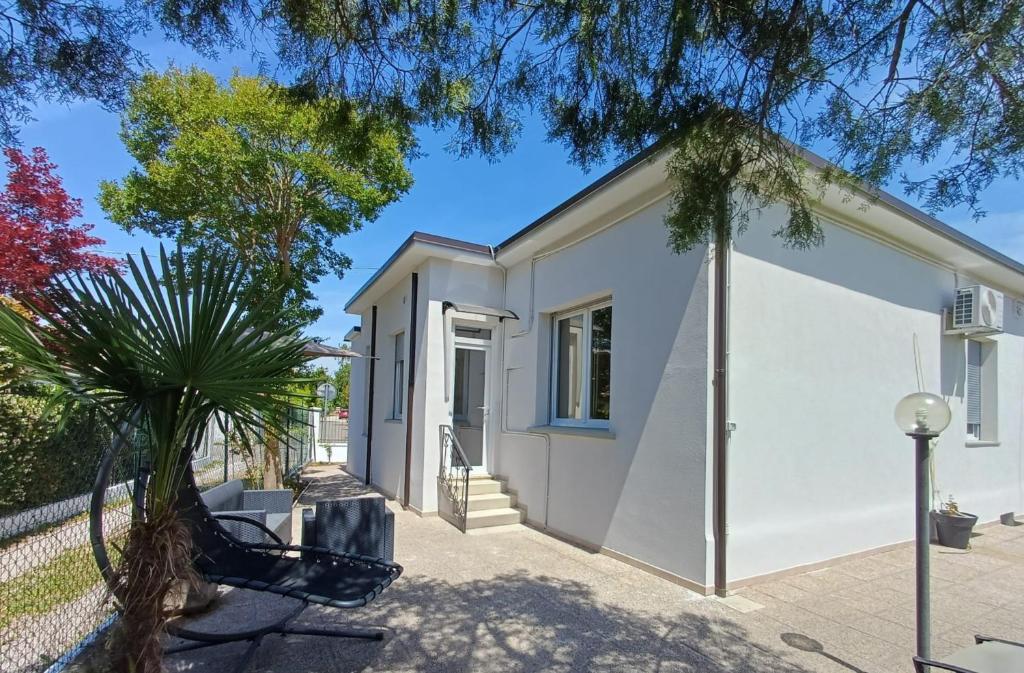 a white house with a tree in front of it at Casa Timavo in Ronchi dei Legionari