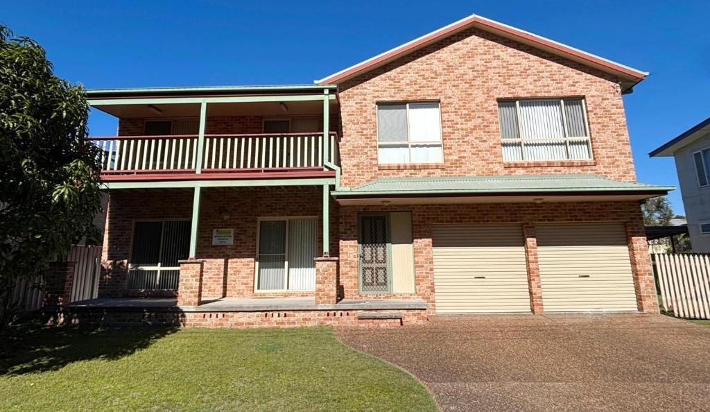 a brick house with a balcony and two garage doors at Parkview Lodge - Bring your own linen. in South West Rocks