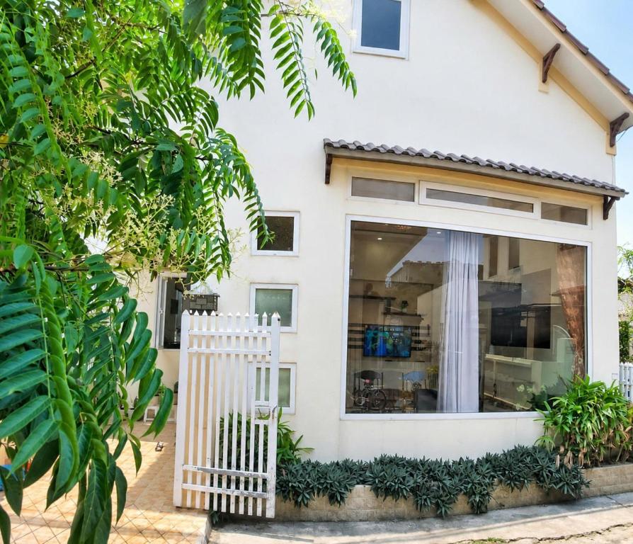 a white house with a white picket fence at The Mellow House Nhật Lệ in Dong Hoi