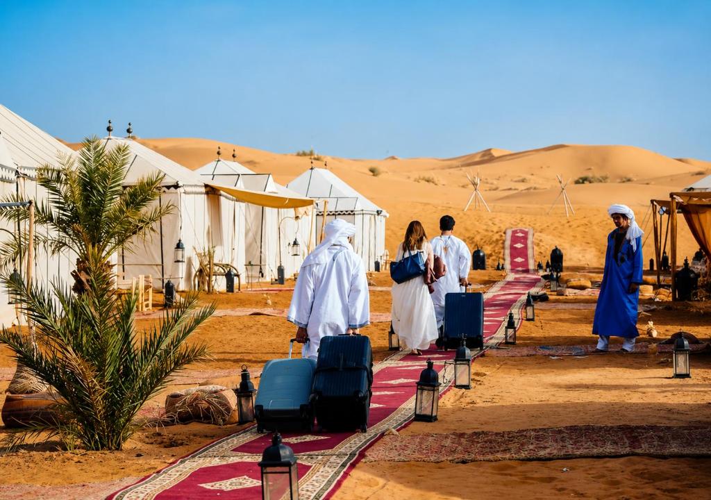 a group of people walking through the desert with luggage at Sahara Luxury Tented Camp in Merzouga