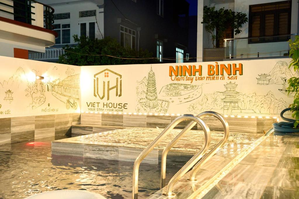 a swimming pool with a sign on the side of a building at Sunny - Việt House in Kỳ Vĩ