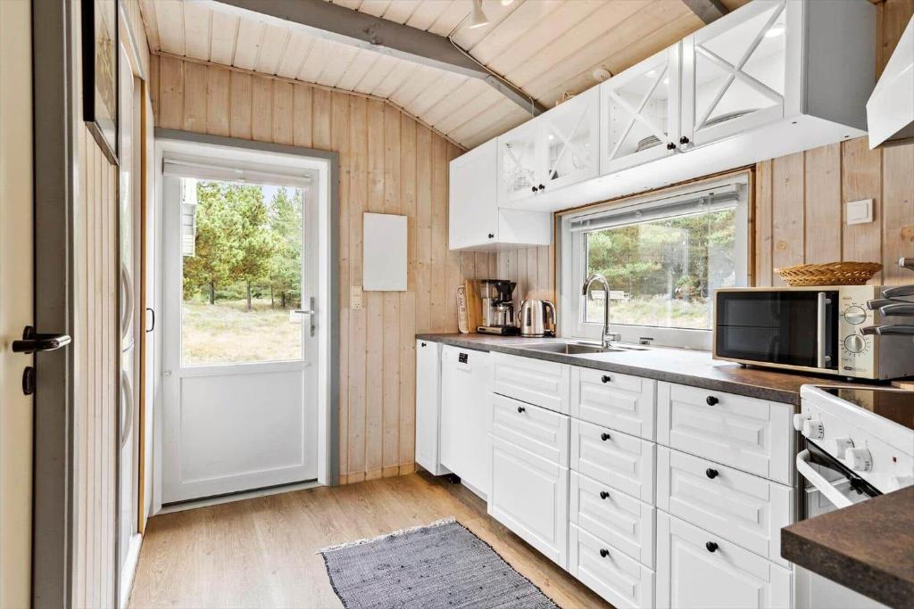 a kitchen with white cabinets and a white door at 0048-Romo-Trinnesvej-12 in Høm