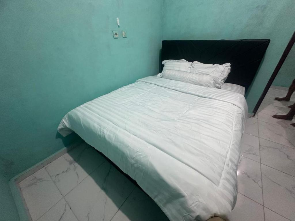 a bed with white sheets and pillows in a room at Novena bungalow Oeseli in Pulau Helihana