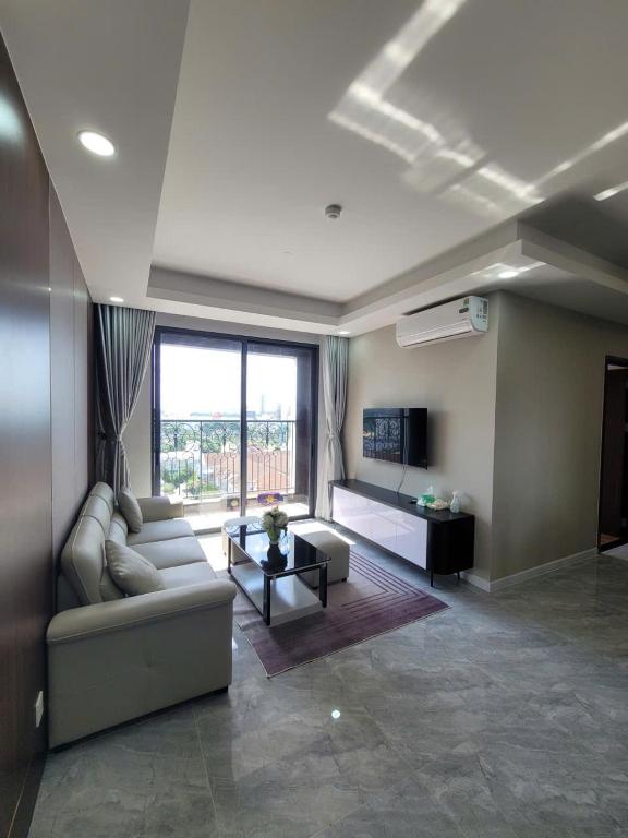 a living room with a couch and a large window at Căn Hộ Cao Cấp Cara River Park in Cái Răng