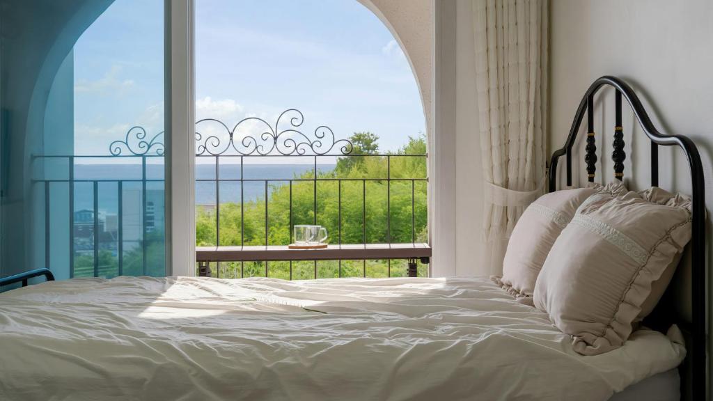 a bedroom with a bed and a large window at Samcheok Sea Road Pension in Samcheok