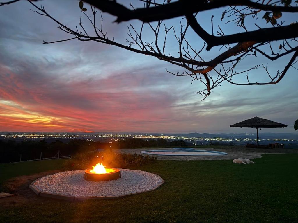 a fire pit in the grass with a sunset in the background at Sítio Paradouro in Novo Hamburgo