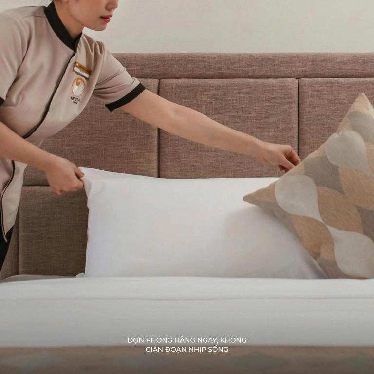 a woman putting a pillow on a bed at Sala Lan Anh hotel in Phước Long