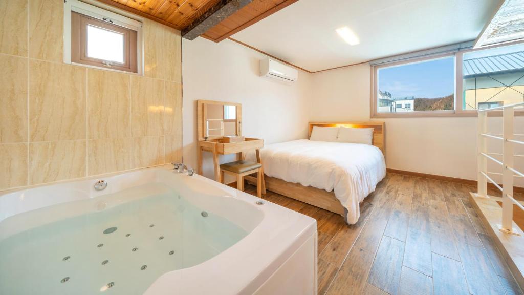 a bathroom with a tub and a bed and a bedroom at Gapyeong Arom Spa Pension in Gapyeong