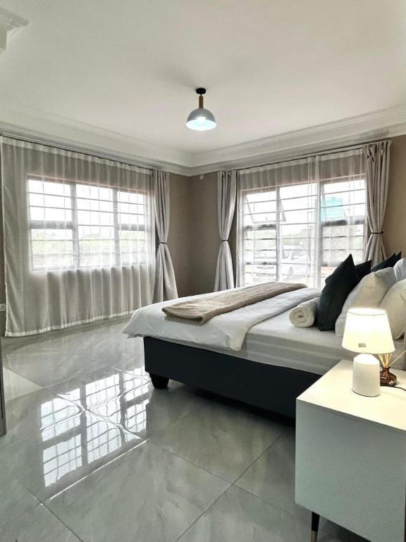 a bedroom with a large bed and windows at Caysa Villa in Gaborone