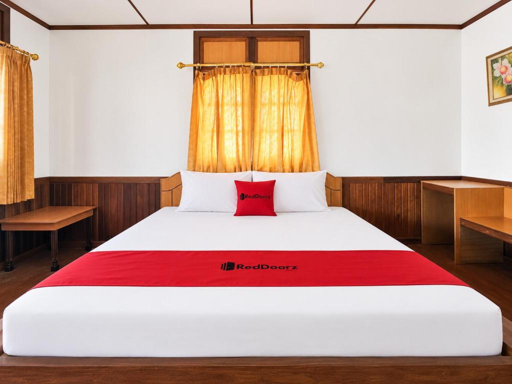 a bedroom with a bed with a red pillow on it at RedDoorz at Derawan Beach Cottage in Derawan Islands