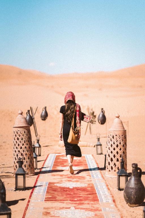 a woman walking down a path in the desert at Royal Erg Chebbi Luxury Camp in Adrouine