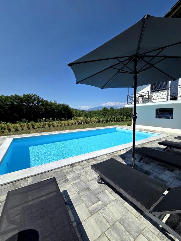 a swimming pool with an umbrella and a table and chairs at Under The Castle in Dob