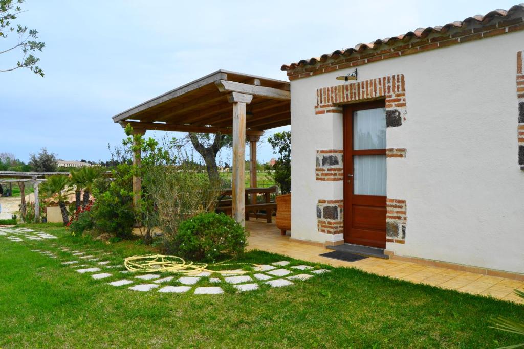 mały biały dom z drewnianymi drzwiami i patio w obiekcie Casa Vacanze Il Pino, Orosei w mieście Orosei