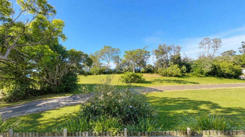 a field of grass with a fence and trees at The Blue Groper in Minnie Water