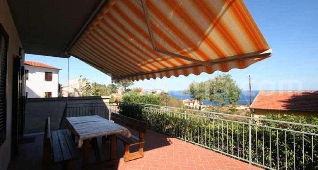 a patio with a table and an umbrella on a balcony at casa la Rosa dei venti in Marciana