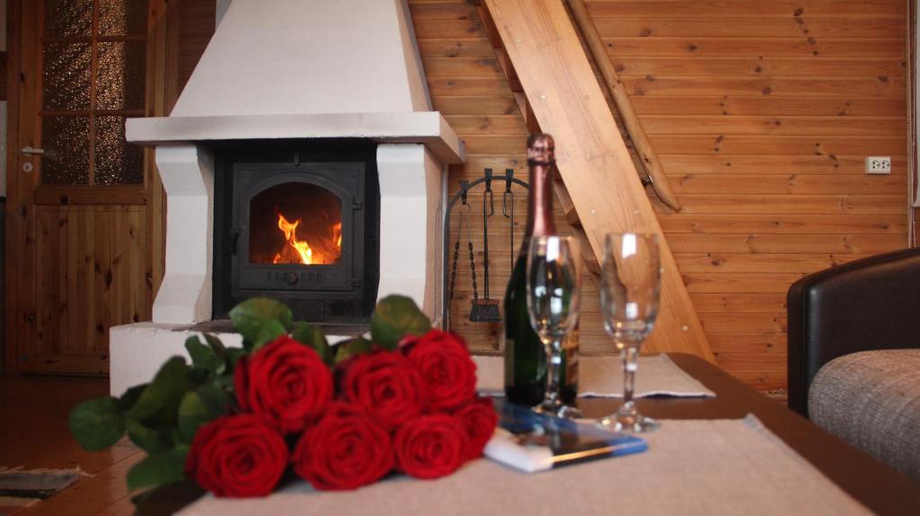 a table with roses and a bottle of wine and a fireplace at Kapteni Holiday House in Paatsalu