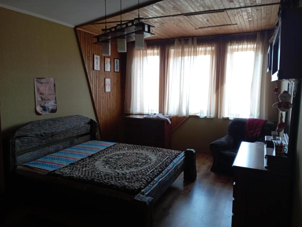 a bedroom with a bed and a couch and windows at Вовча хижа in Khmelnytskyi