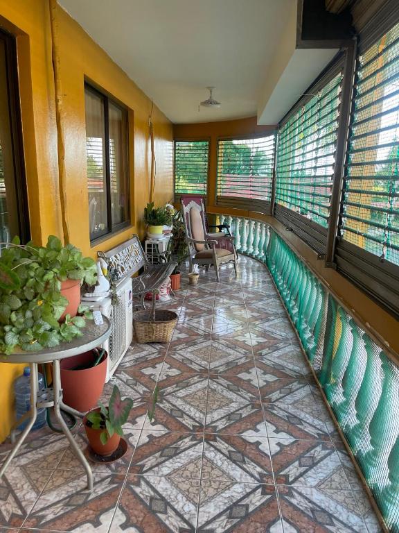 a balcony with a tiled floor with chairs and windows at Edna's GuestHouse in Siquirres