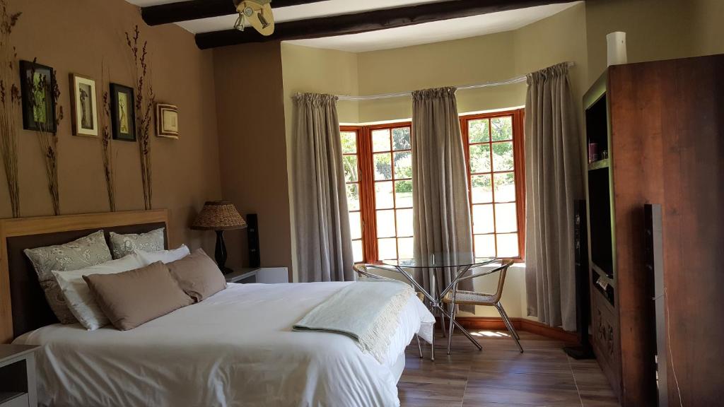 a bedroom with a large white bed and windows at Tuckaway in Somerset West