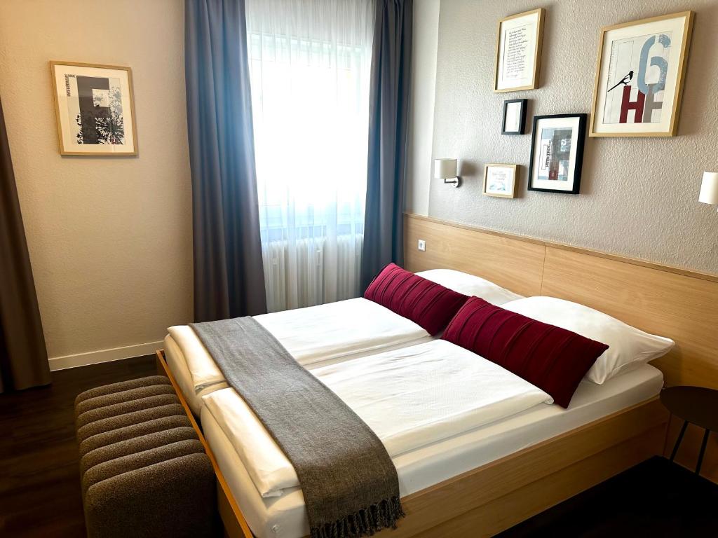 a bedroom with a bed with red pillows and a window at Hotel Friedrichstraße in Lampertheim