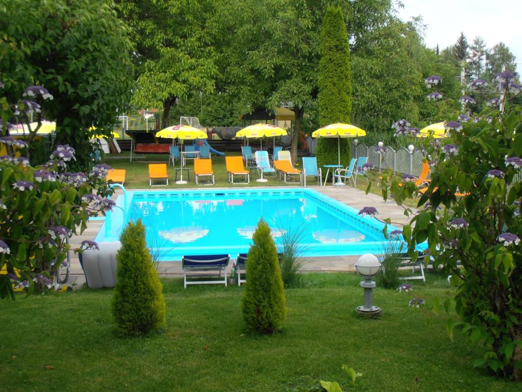 a swimming pool with chairs and umbrellas in a yard at Ferienanlage Seehof in Krumpendorf am Wörthersee