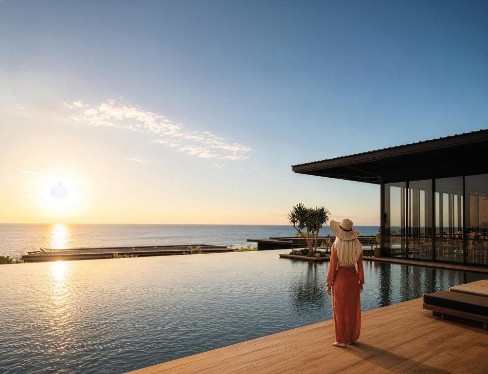 a woman standing on a deck looking at the ocean at Wood Hôtel & Spa in Saint-Gilles-les-Bains