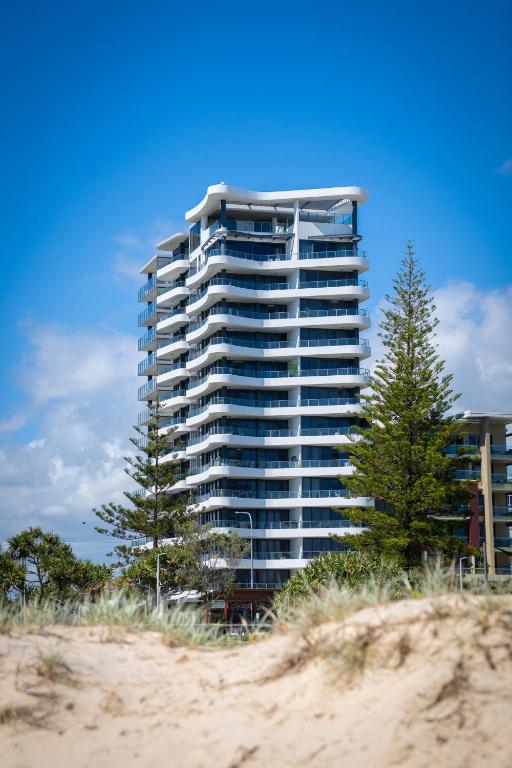 a tall building with trees in front of a beach at X Kirra Apartments in Gold Coast