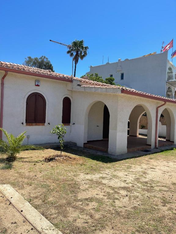 an old white house with a palm tree in the background at Villino Sicaru' in Simius
