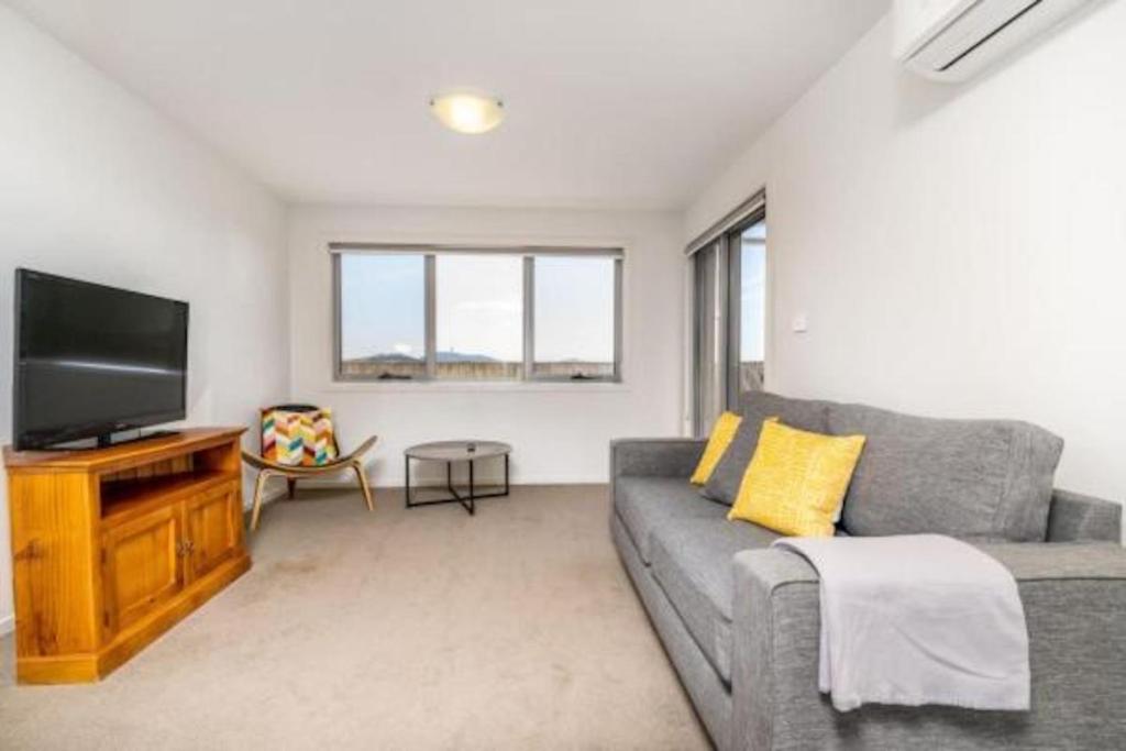 a living room with a couch and a flat screen tv at Relaxing 2BR Apt in North Point Complex - Hosted by Canstay in Weston Creek