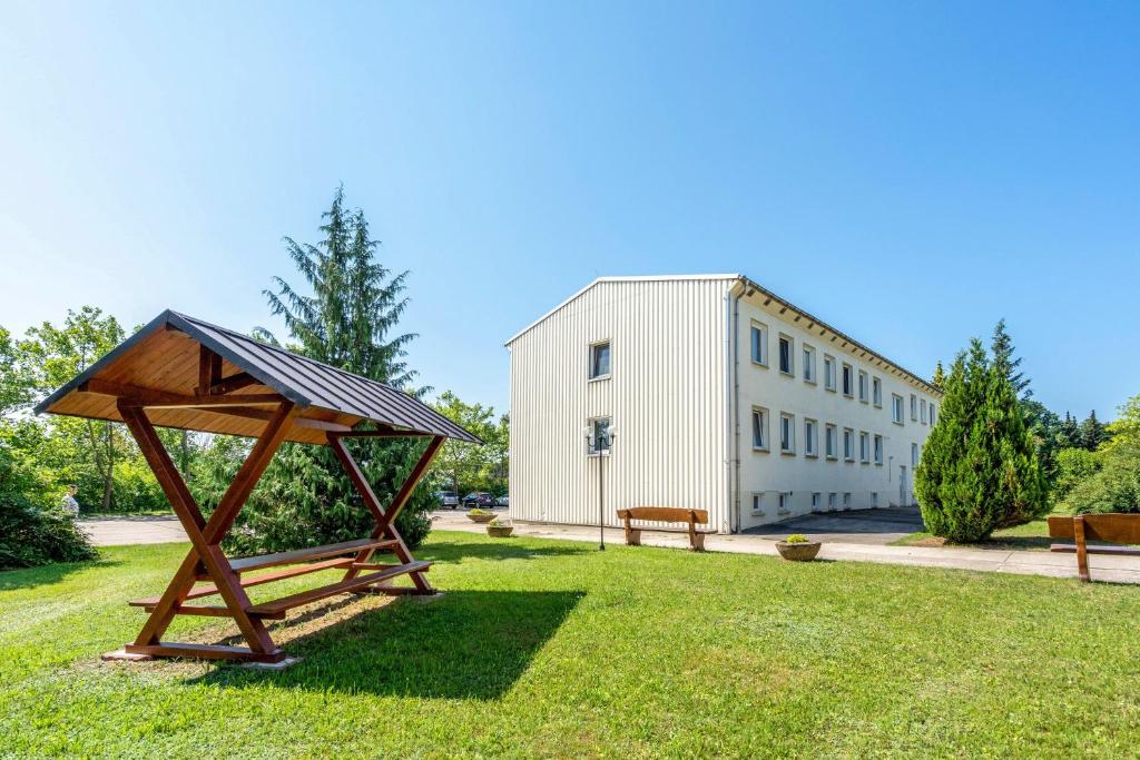a wooden structure in the grass in front of a building at Pension Clara in Klipphausen