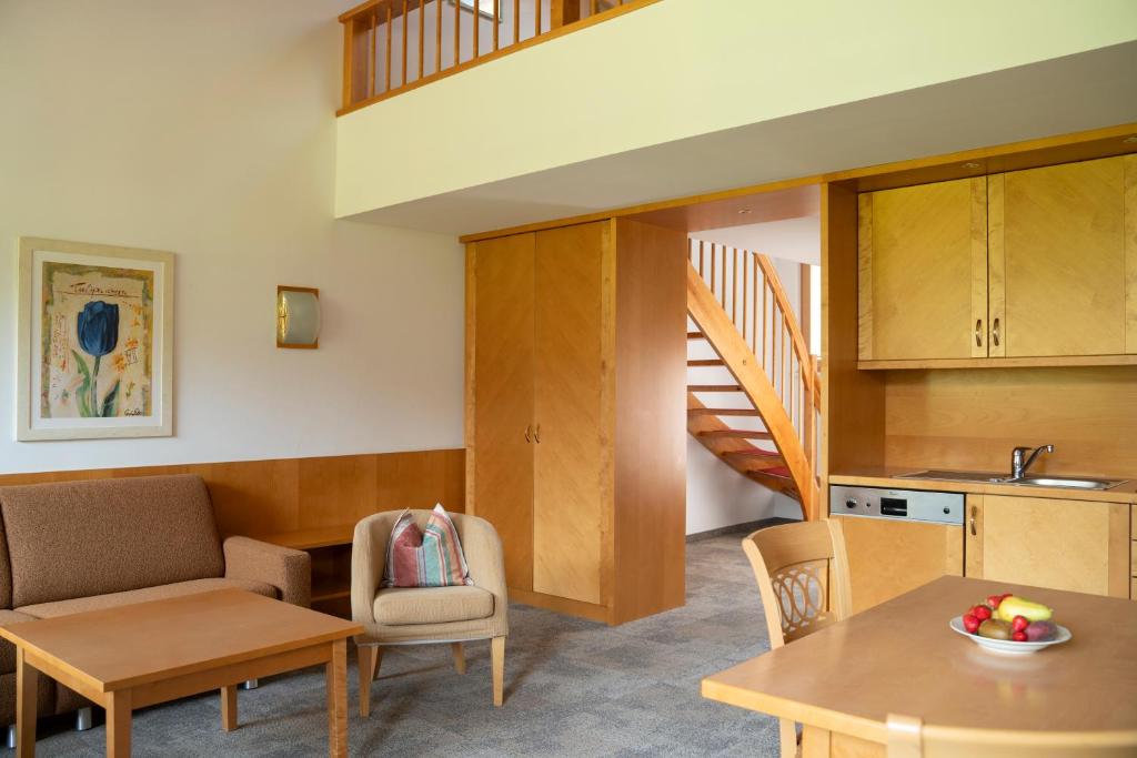 a living room with a kitchen and a staircase at Aparthotel Schindlhaus/Alpin in Söll