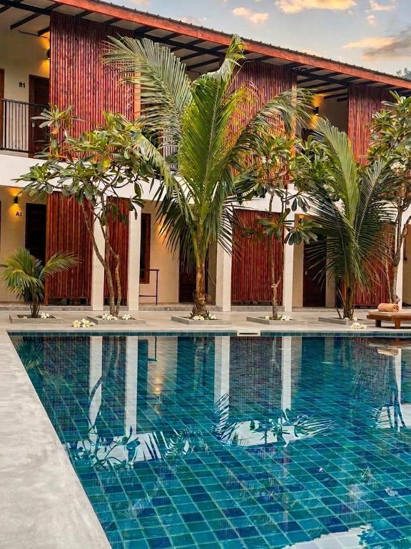 a swimming pool in front of a building with palm trees at Mountainblues Hotel in Pai