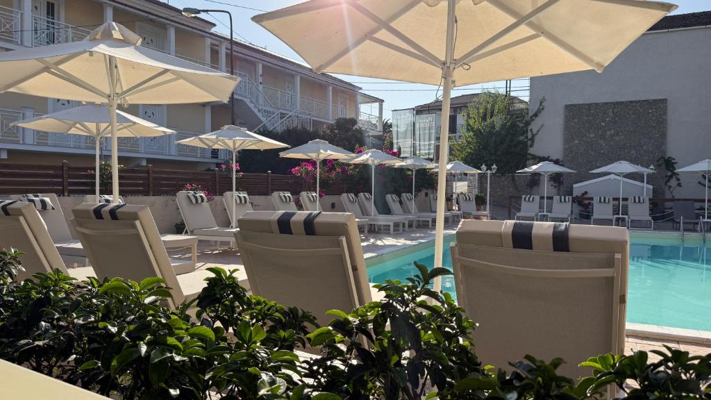 a group of chairs and umbrellas next to a pool at The Mathraki Studios in Arillas