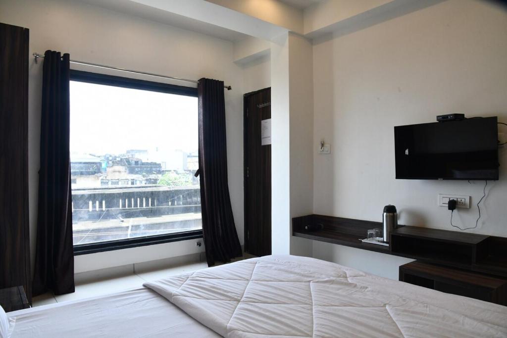 a bedroom with a bed and a large window at Hotel Shreeji Palace in Ābu Road