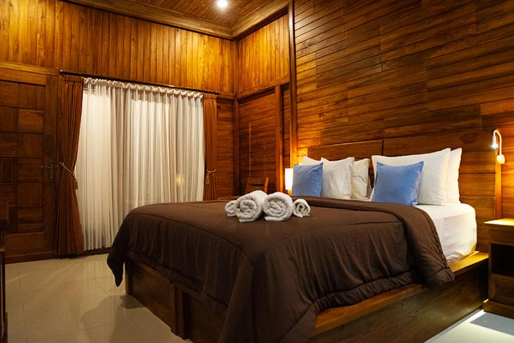 a bedroom with a large bed with wooden walls at Pemedal Beach Resort in Nusa Lembongan