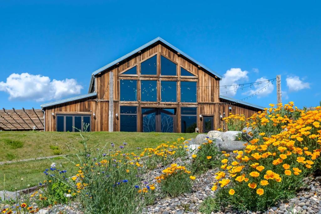 a barn with a field of flowers in front of it at Yellowstone Valley Lodge, an Ascend Collection Hotel in Pray
