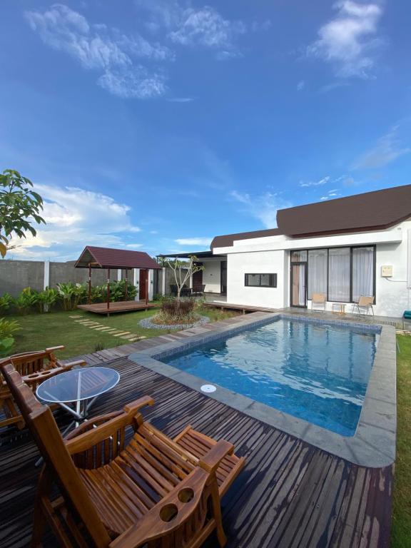 a swimming pool with chairs and a house at Svaha Ubud Villas in Siantan