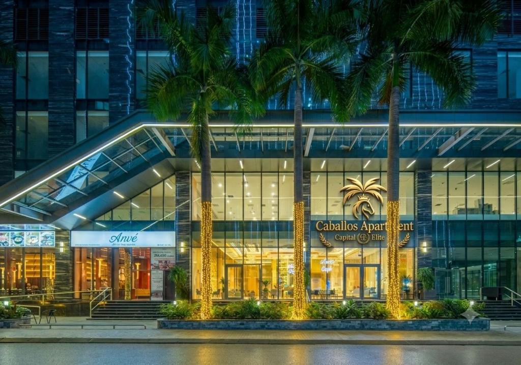 a building with palm trees in front of it at Caballos Apartment Capital Elite in Hanoi