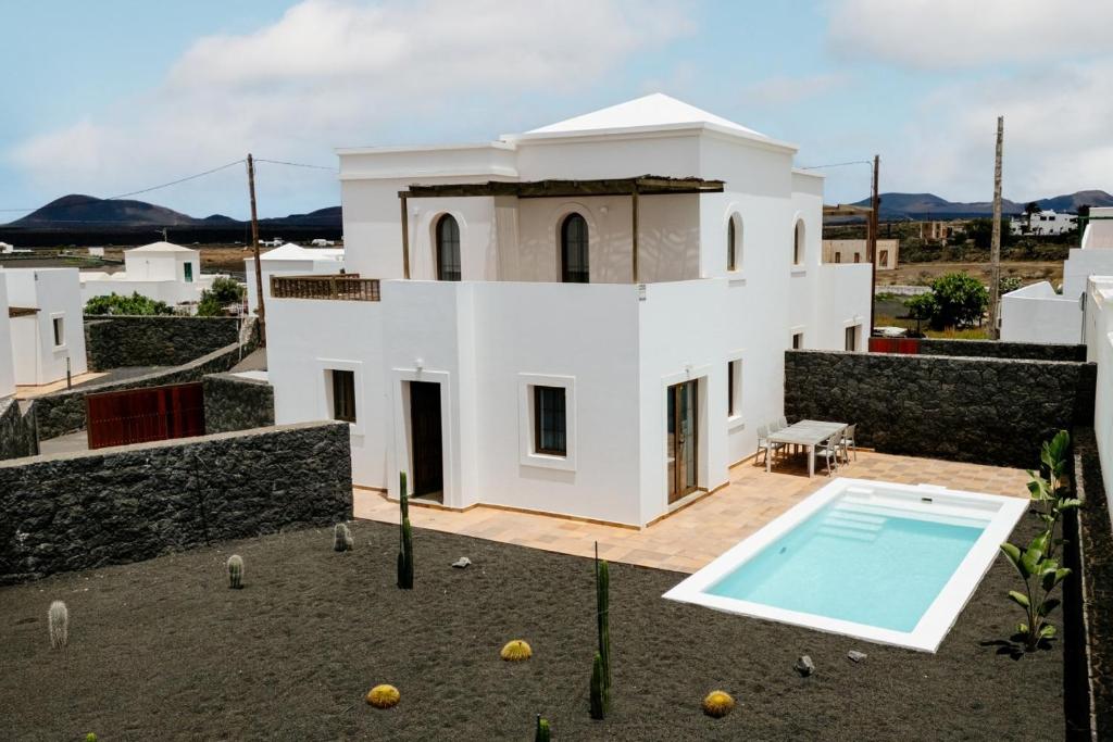 a white house with a swimming pool in front of it at Villa Volcano by CasasBlancas in Yaiza