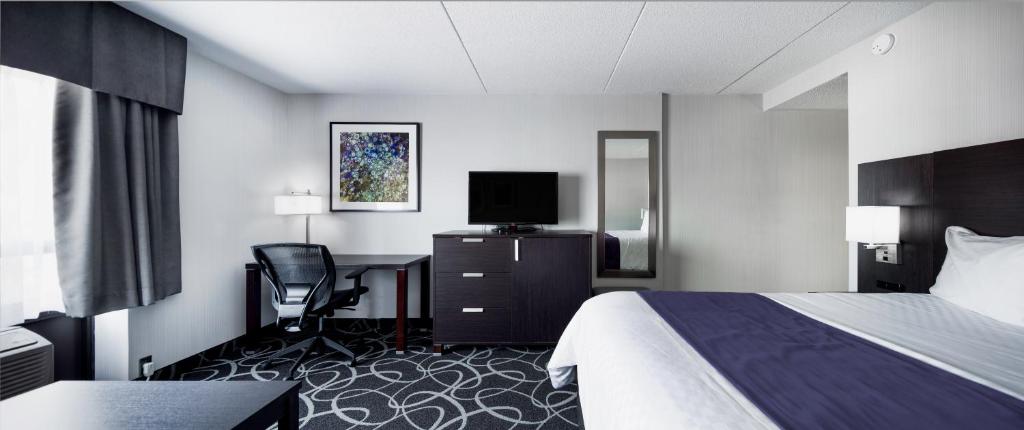 a hotel room with a bed and a desk and a television at Stonecroft Inn in Windsor