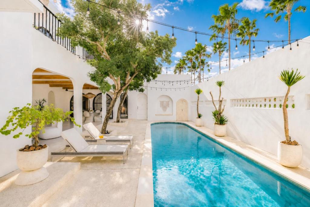 a pool in a villa with palm trees and chairs at Casa Contenta Canggu - Luxury 5BR Private Pool Villa in Canggu