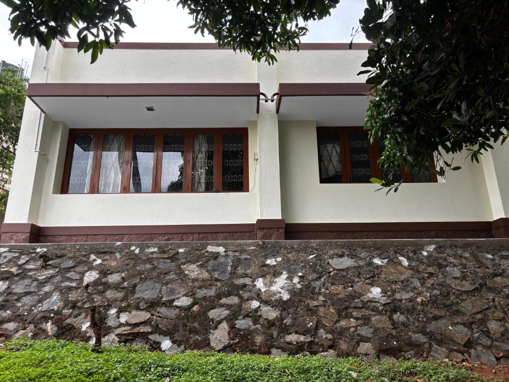 a house with a stone wall in front of it at Oakville in Mysore