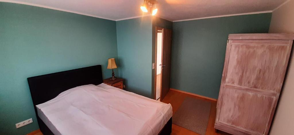 a bedroom with a white bed and a green wall at Herzstück Ferienwohnung Waxweiler in Waxweiler