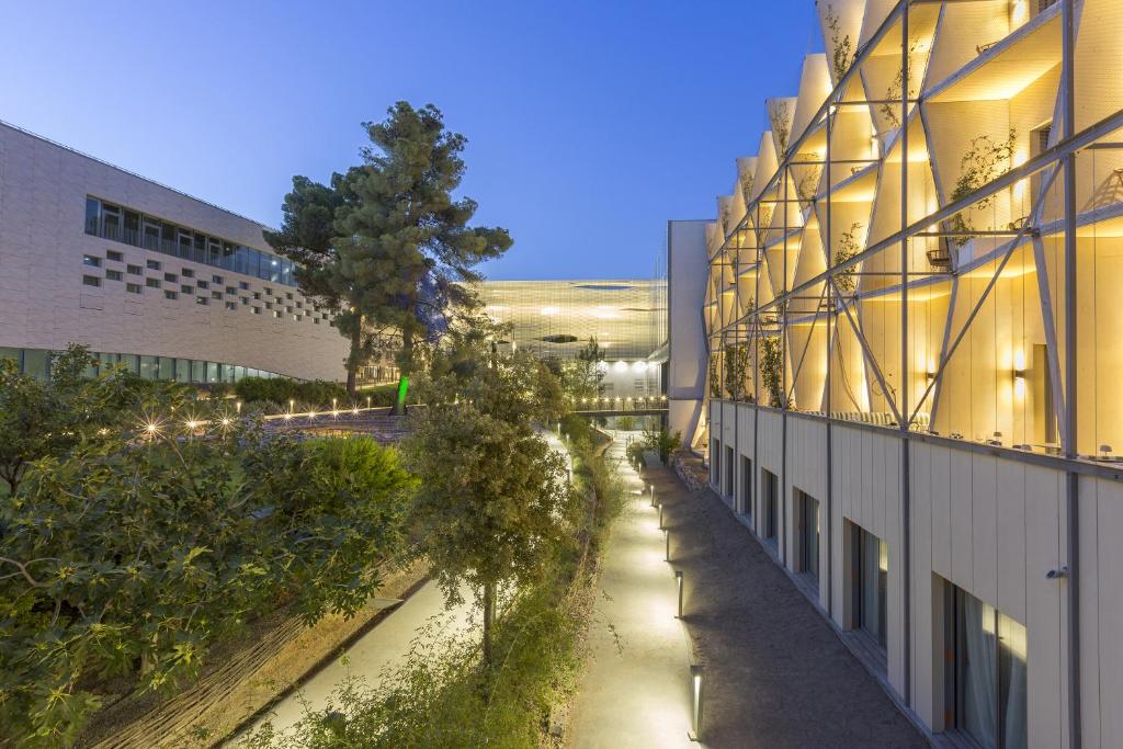 an alley between two buildings with trees on the side at SOWELL HÔTELS Villa Arena in Nîmes