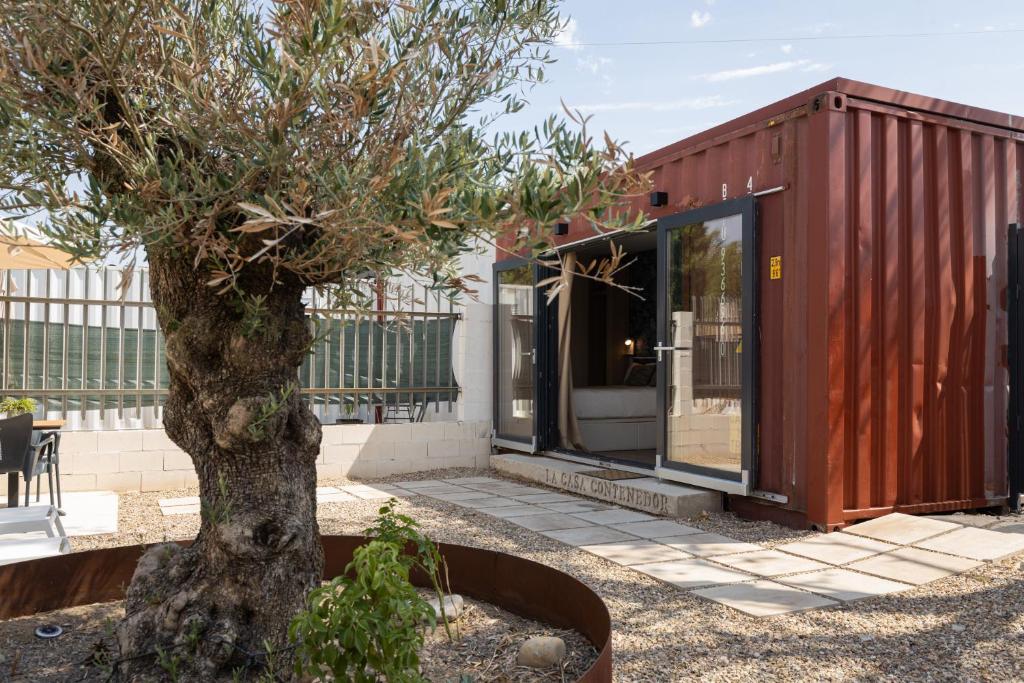 a tree in front of a house with a building at La Casa Contenedor Loft in Zaragoza