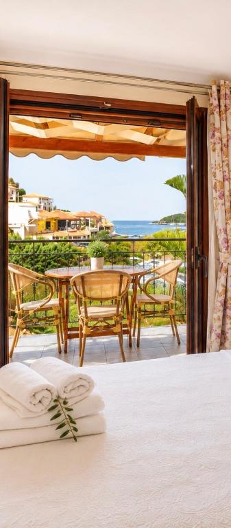 a bedroom with a bed and a balcony with a table and chairs at Angela Studios in Syvota